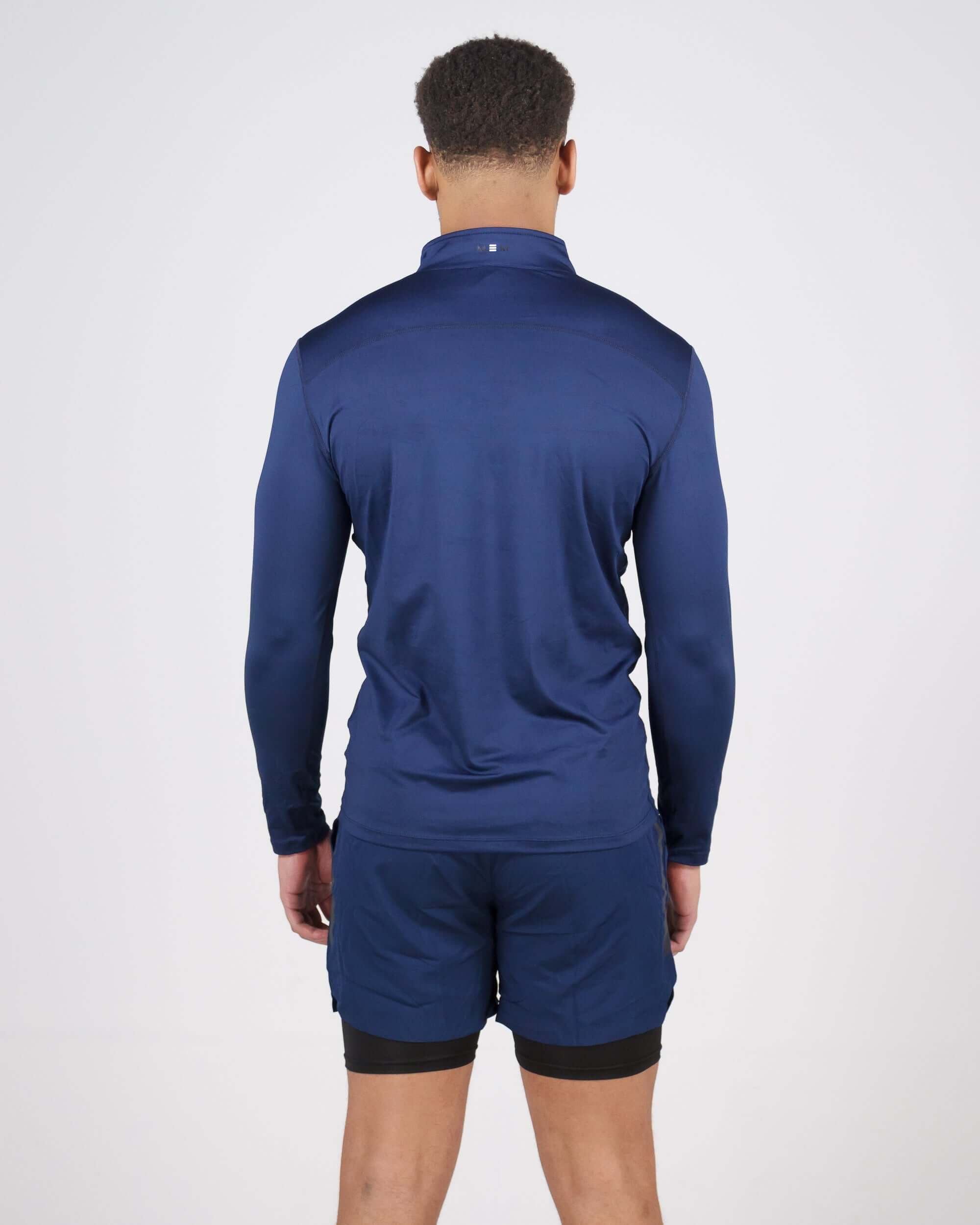 Back view of navy Pinnacle Dry-Fit Long Sleeve Half Zip Training Top worn by model, highlighting athletic fit and moisture-wicking fabric.