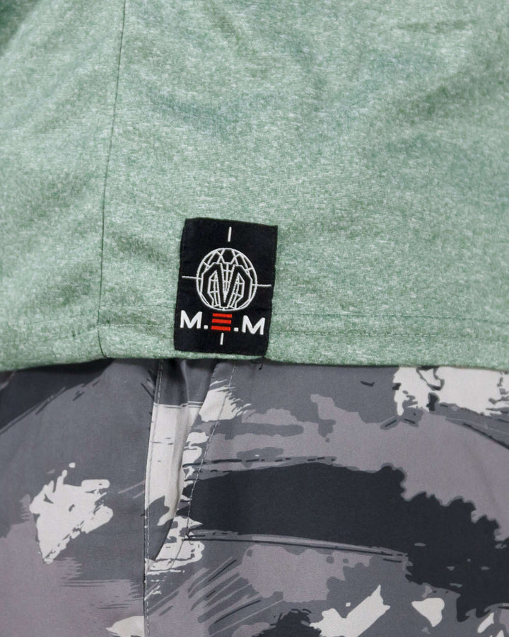 Close-up of a light green Pinnacle Slim Fit Tank Top logo, paired with abstract-patterned workout leggings.