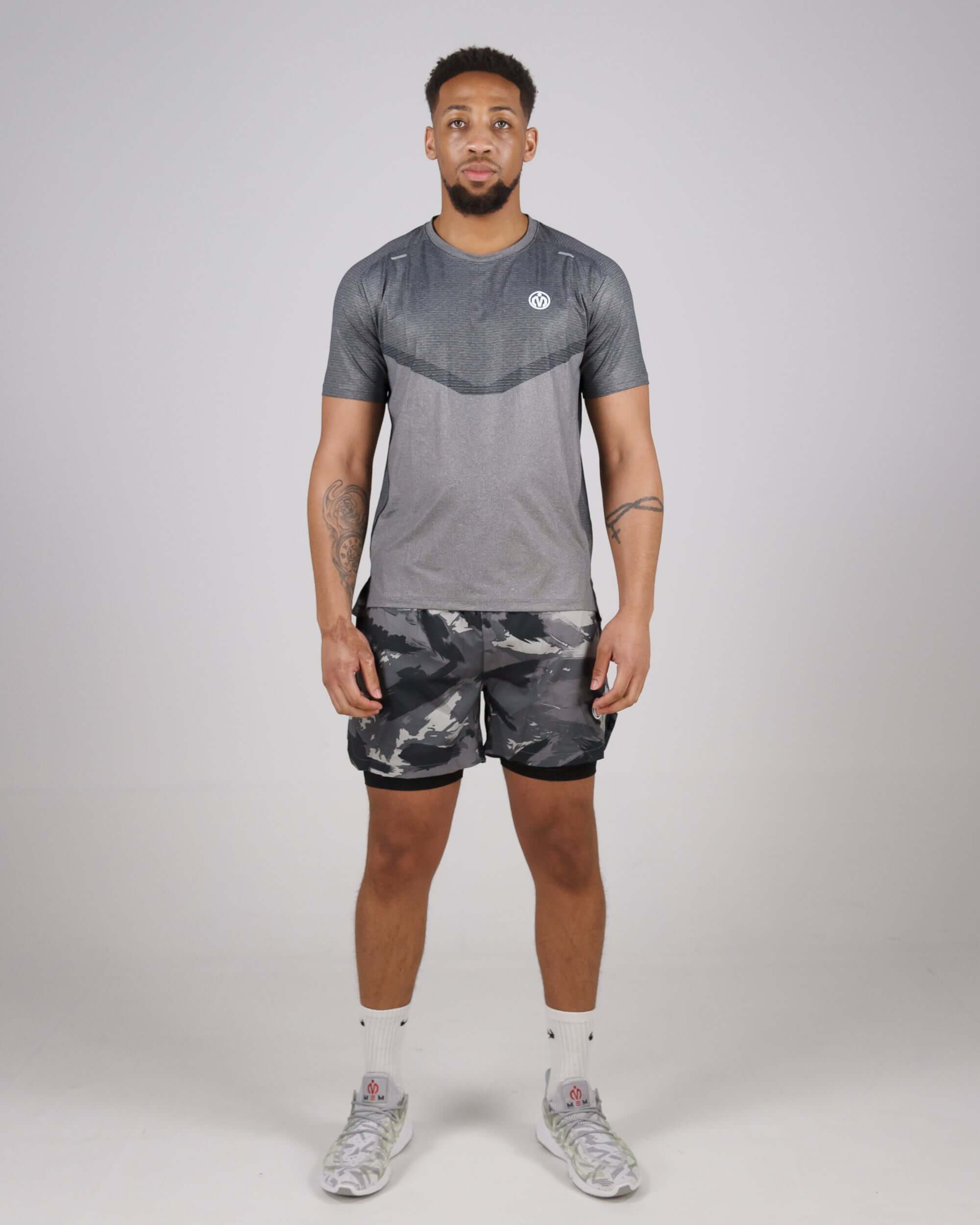 Man wearing MEM Pinnacle Dry-Fit Training Top and camo shorts, showcasing gym apparel designed with cutting-edge performance technology.