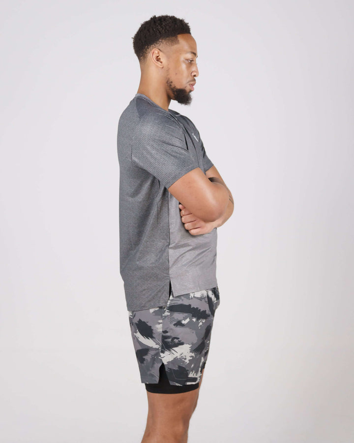 Man wearing grey Pinnacle Dry-Fit T-Shirt with camo shorts standing sideways.