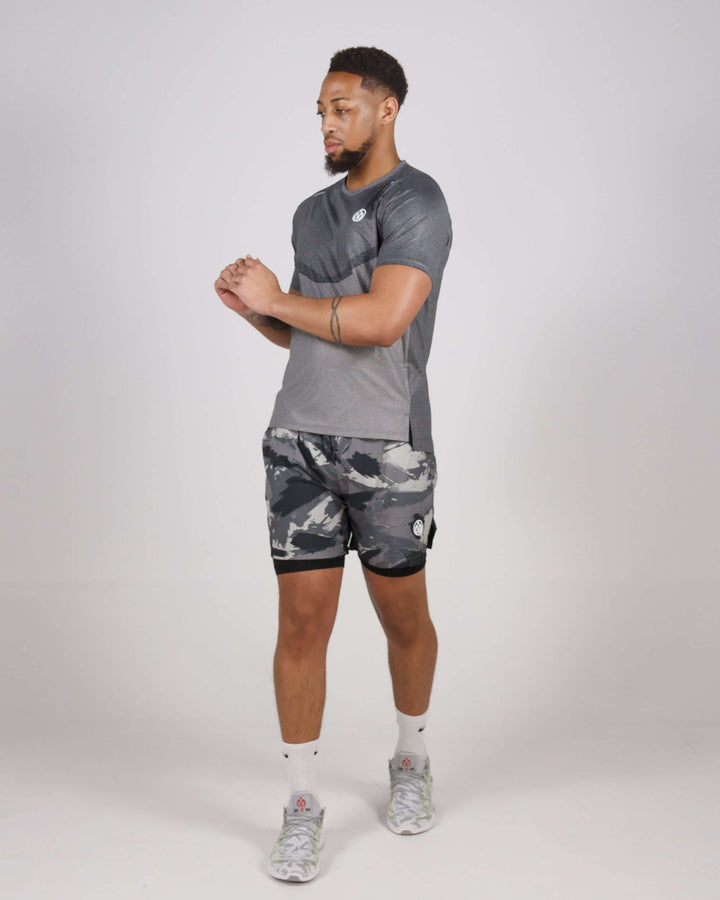 Man wearing MEM Pinnacle Dry-Fit Training Top and camo shorts in studio setting