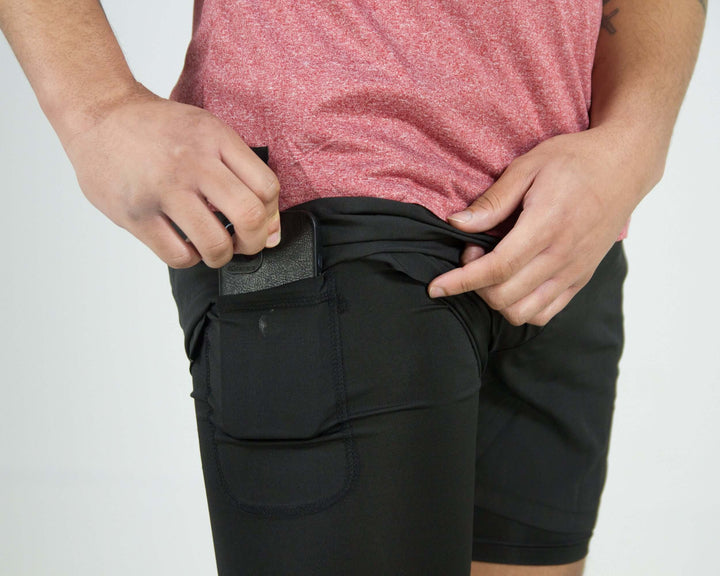 Close-up of person wearing black Pinnacle Dry-Fit 2-in-1 Shorts, showing the innovative pocket design.